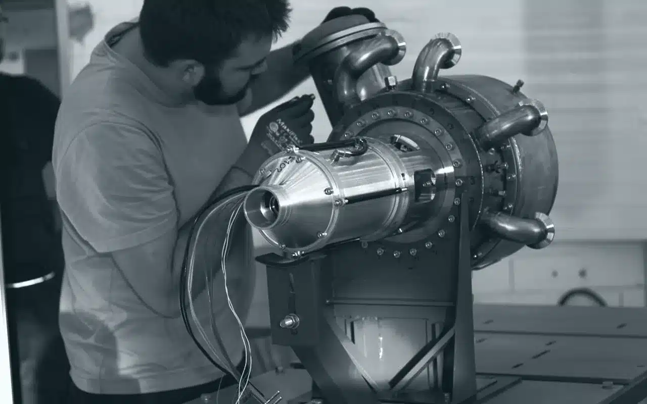 Kollege bei der Arbeit an einer Mikrogasturbine mit Heißgasleitungen